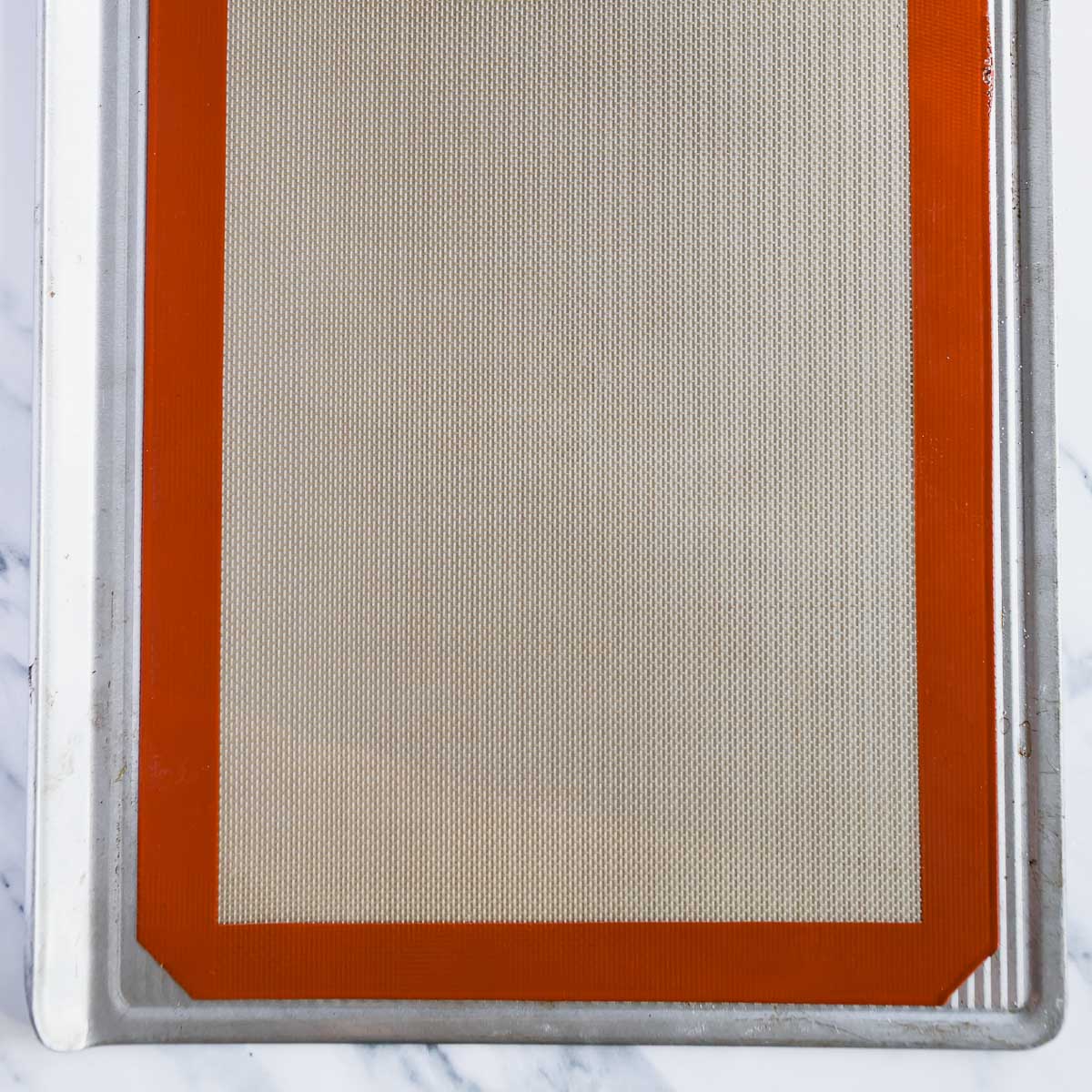 Lining a baking tray with a silpat mat for baking meringues and macarons.