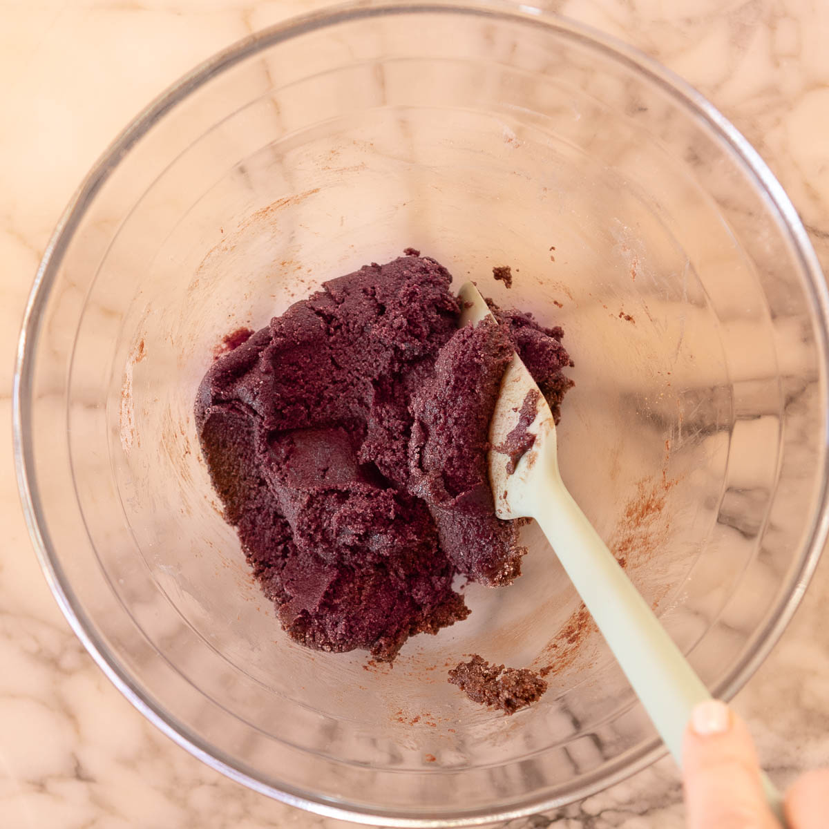 Mixing red food colour into macaron paste.