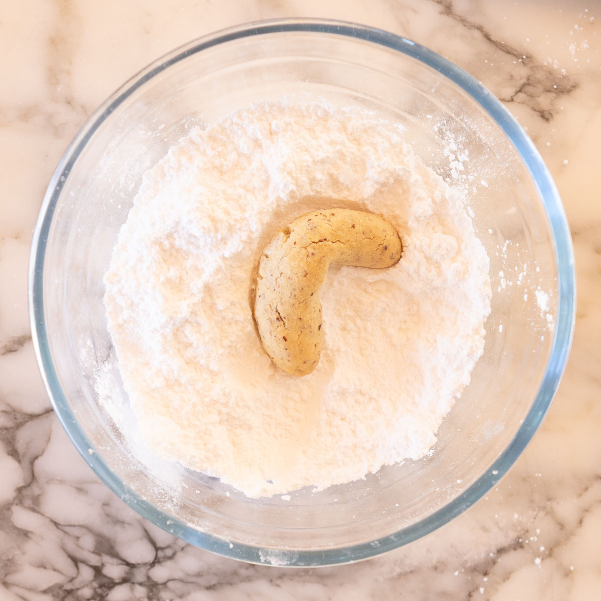 Coating the cooked shortbread in icing sugar.