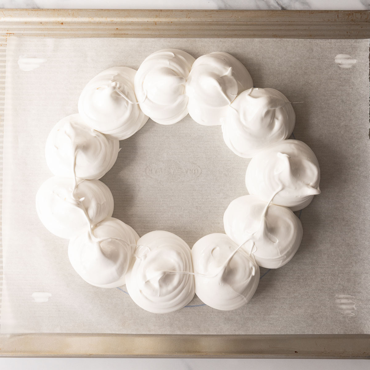 Pipe individual mounds of meringue onto the baking paper, to make the Christmas pavlova wreath.