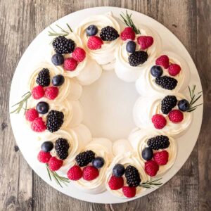 A Christmas Pavlova Wreath, decorated with chantilly cream and fresh berries.