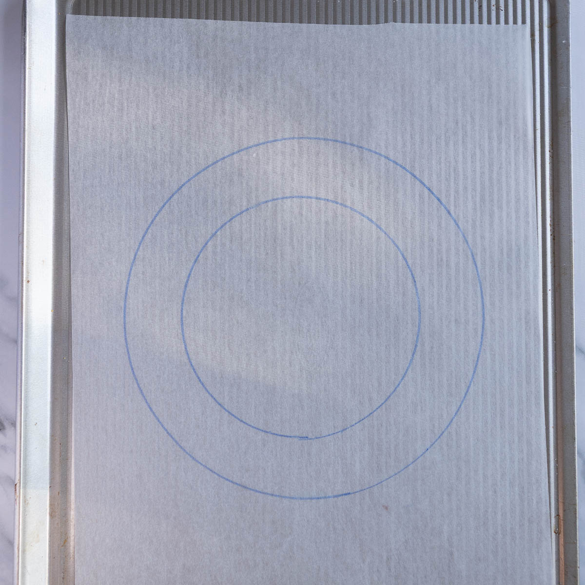 Two circles drawn on baking paper and placed onto a baking sheet, to use as a template for the christmas pavlova wreath.