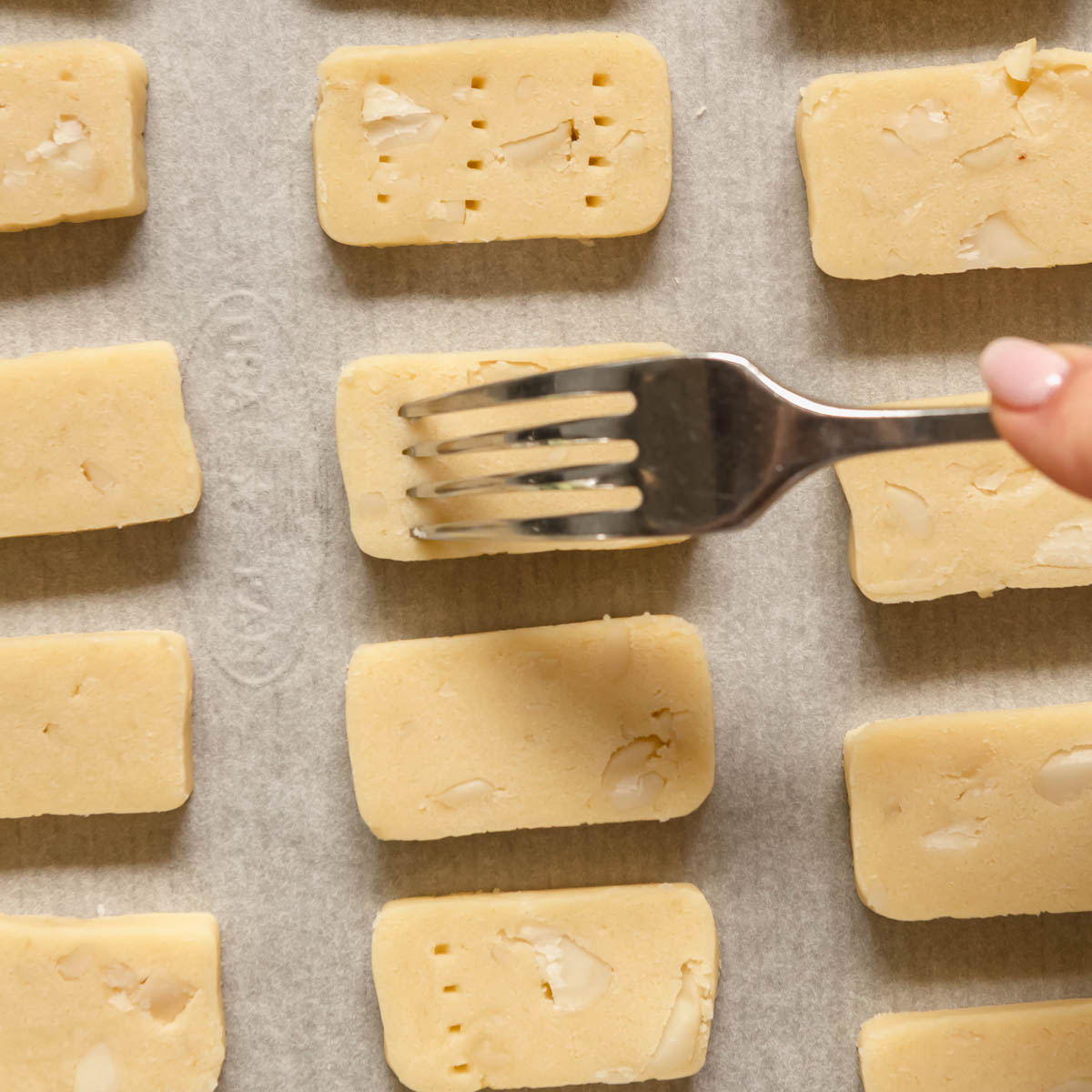 After cutting shortbread into slices, each one is pressed with a fork 3 times, for a traditional shortbread look.