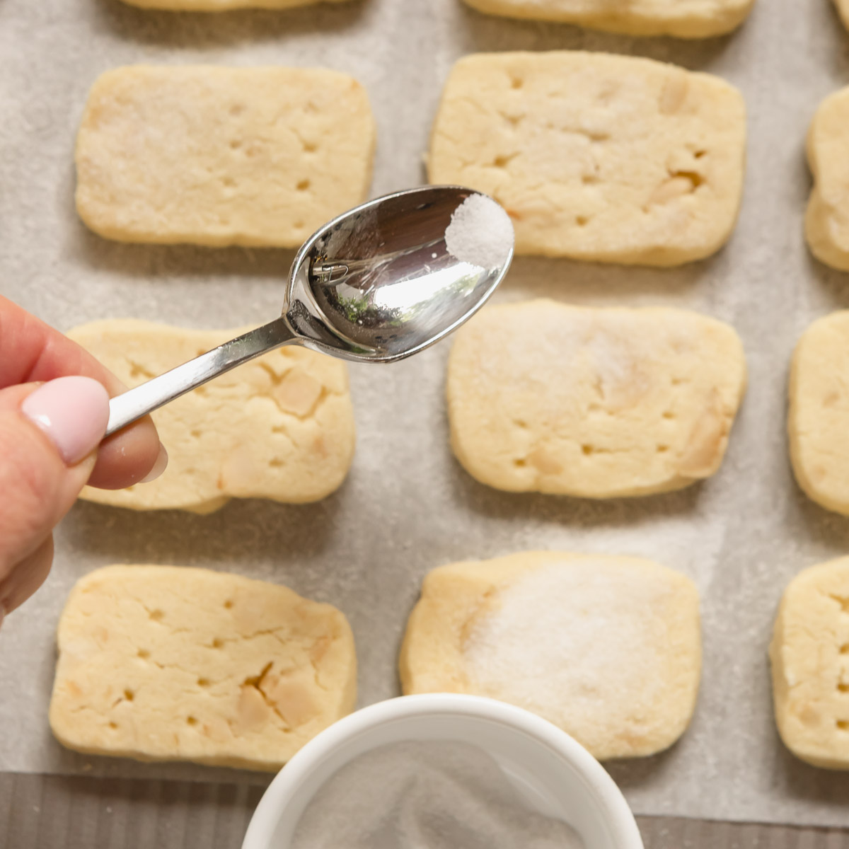 Coating the madacamia nut shortbread with extra sugar after baking.
