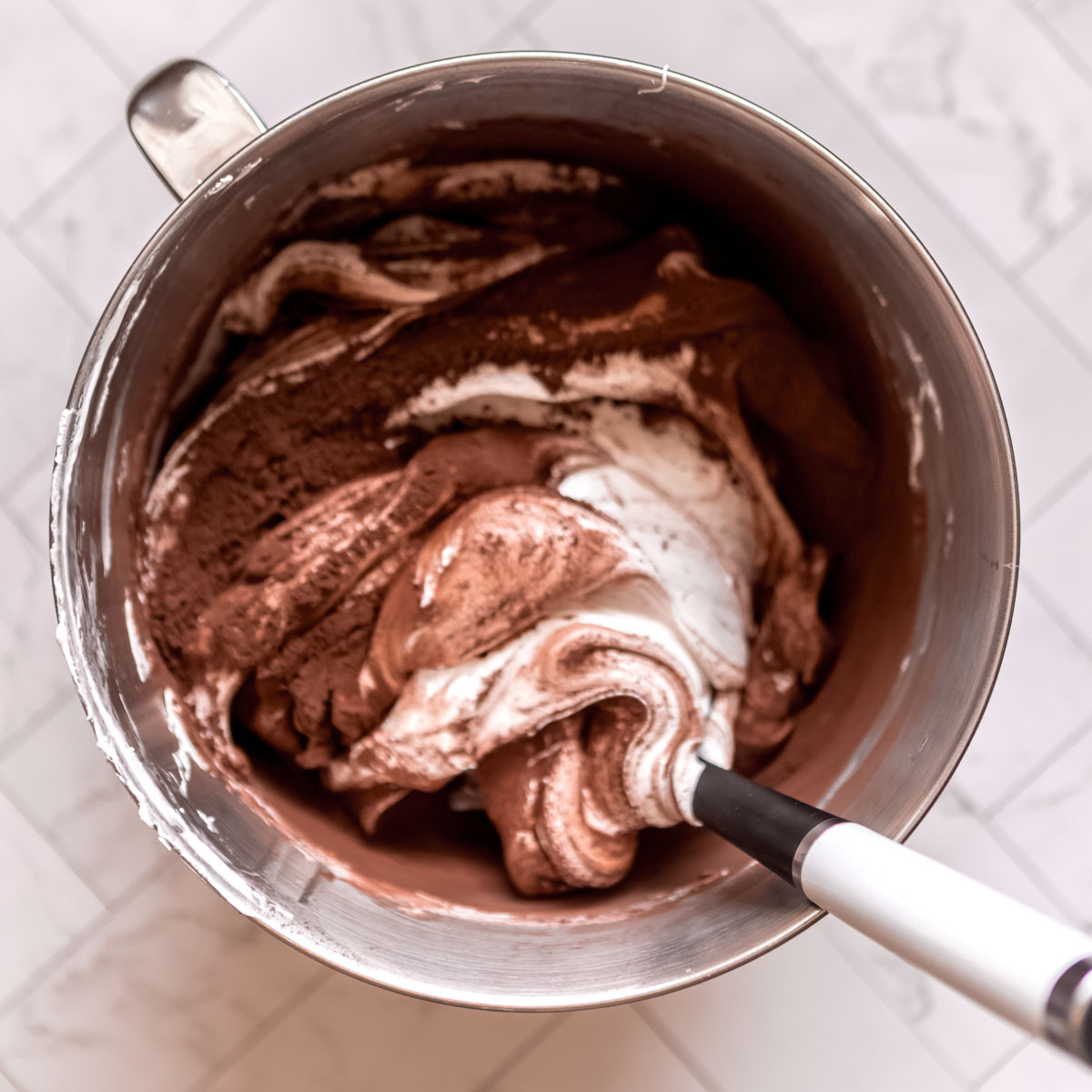 Folding sifted cocoa into meringue, to make chocolate pavlova.