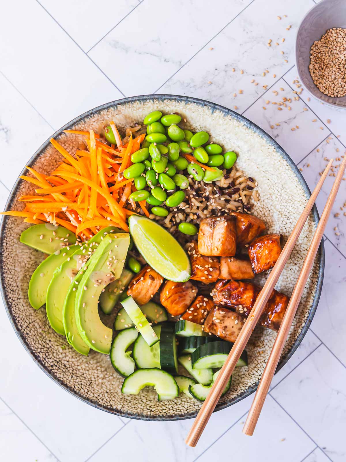 Sticky honey soy salmon bowl, with fresh vegetables, rice and sesame seeds.