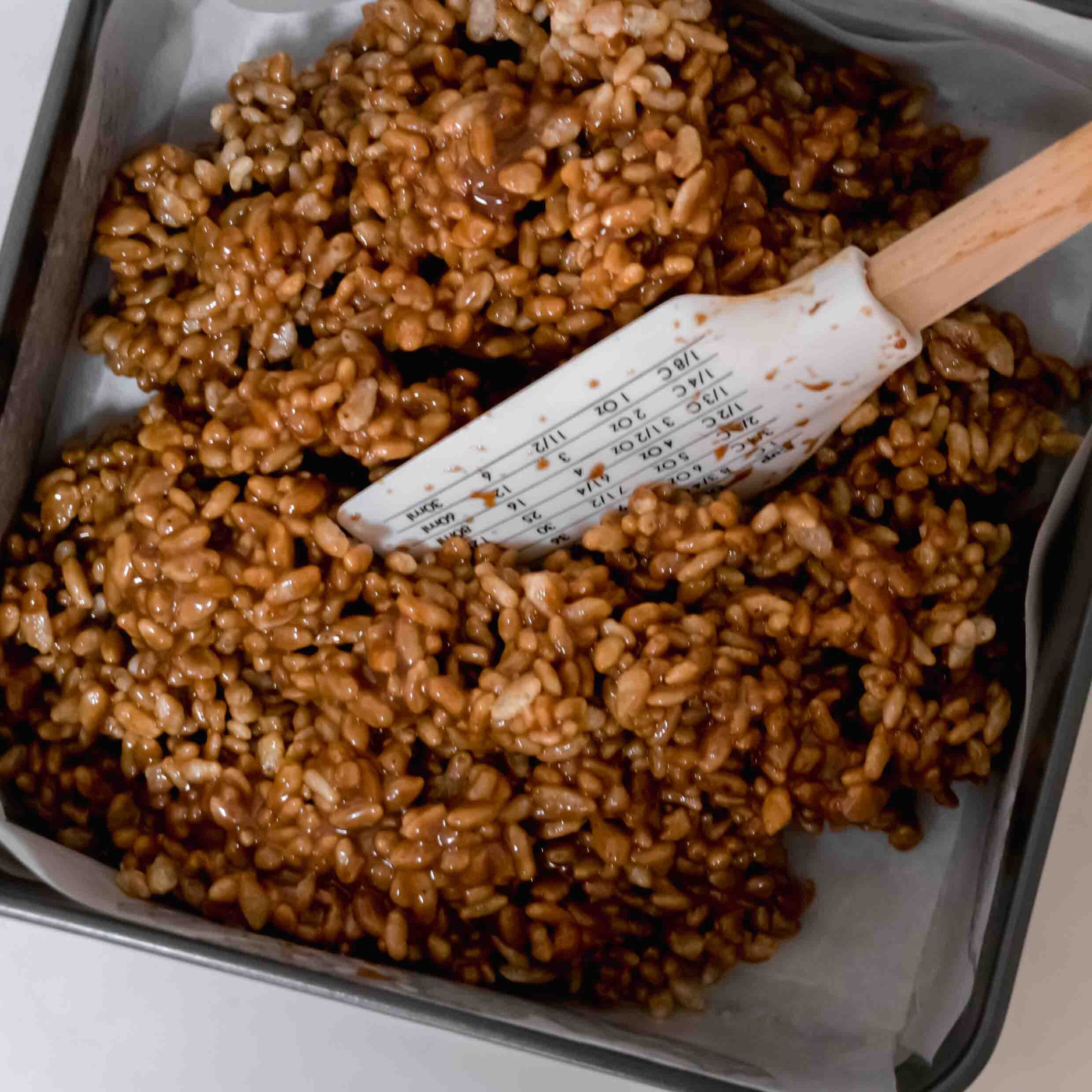 Pressing Mars Bar Mixture into a lined tin.
